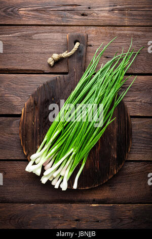 Grüne Zwiebel oder Schalotte auf Holzbrett, frischem Schnittlauch Stockfoto