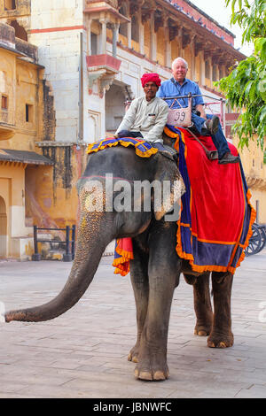 Elefant mit Touristen zu Fuß in Jaleb Chowk (Ehrenhof) in Amber Fort, Rajasthan, Indien eingerichtet. Elefantenreiten sind beliebte Touristenattraktion Stockfoto