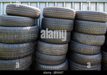 drei Stapel von gebrauchten Altreifen vor einem container Stockfoto