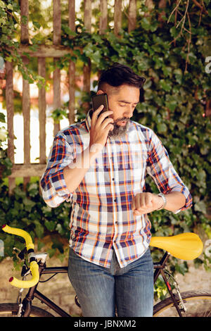 Lässige Geschäftsmann mit Fahrrad am Smartphone sprechen. Stockfoto