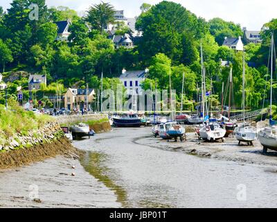 Boote bei Ebbe, umgeben von Häusern, die über den Fluss Aven in der Bretagne auf Hügeln gebaut. Pont-Aven, Frankreich. Stockfoto