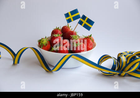 Erdbeeren mit Schweden Flaggen in einer weißen Porzellanschüssel mit weißem Hintergrund. Stockfoto