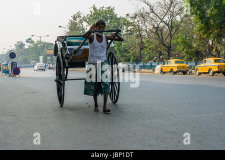 Ein Mann zieht eine Rikscha, auf der Suche nach Kunden, auf einer Straße in der Vorstadt Esplanade