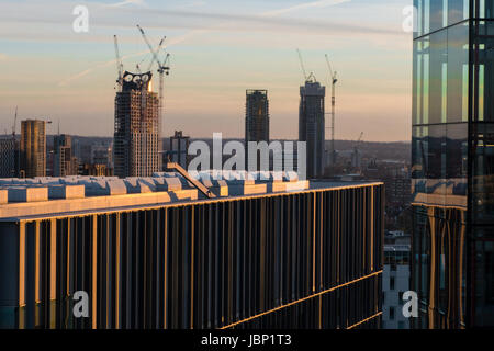 Details der Büro- und Wohnhäuser gegen London Skyline im Sonnenuntergang mit Hochhaus Bauarbeiten und Krane Stockfoto