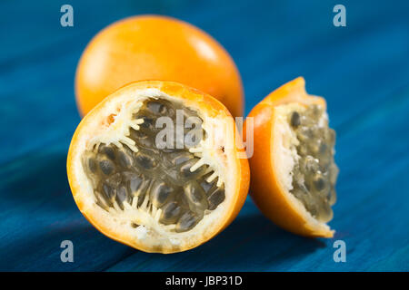 Süße Granadilla oder Grenadia (lat. Passiflora Ligularis) Frucht halbieren, von denen die Samen und die umliegenden saftiges Fruchtfleisch wird gegessen oder wird verwendet, um Saft zu bereiten (selektiven Fokus, Fokus auf der Vorderseite der Samen) Stockfoto