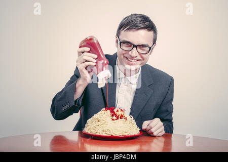 Positiven Konsum Konzept. Glücklich Kaufmann Ketchup auf große Schüssel Nudeln gießen. Stockfoto