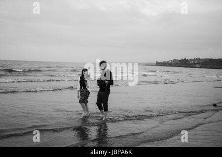 Ein paar paddeln durch West Sands, St Andrews.   Am Strand sind Ebbe Wellen cresting. Stockfoto