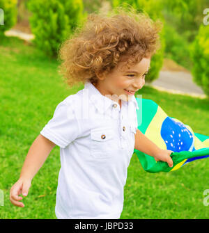 Porträt von niedlichen kleinen Jungen mit Brasilien Nationalflagge, fröhliche junge Fußballspieler, Fan der brasilianischen Fußball-Nationalmannschaft Stockfoto
