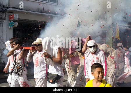 Tragen eine Statuen der Götter unter einem Hagel von chinesischen Feuerwerkskörper in einer Parade während des neun Kaiser Götter Festivals (vegetarische Festival) in Phuket, Stockfoto