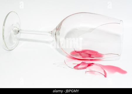 Zerbrochene Schwenker Glas mit spritzte verschüttete roten Wein und scharfe Splitter auf Hintergrund Stockfoto