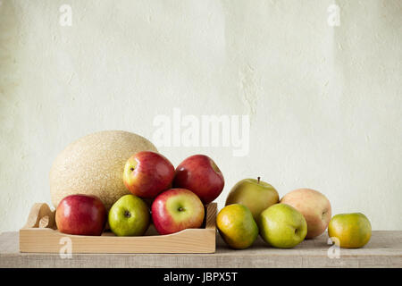 Viele Früchte auf einem Holztablett mit einem Wand-Hintergrund. Stockfoto