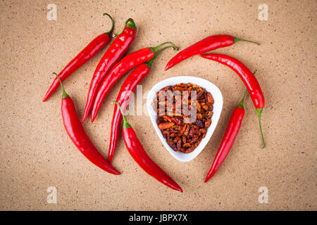 Frische und getrocknete rote scharfe Chilischoten auf Holztisch. Stockfoto