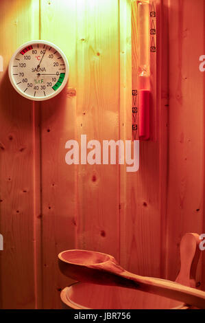 Saunazubehör aus Aufgußeimer, Saunakelle, Sanduhr Und Temperaturmesser Zeit Vor Sauna-Holzwand Stockfoto