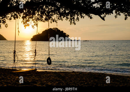 Eine Schaukel und ein Reifen schwingen bei Sonnenuntergang am Strand von Teluk Nipah, Pangkor Island (Pulau Pangkor), der West-Malaysia Küste. Stockfoto