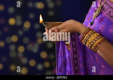 Diwali oder festliche Lichter. Traditionelle Indianerfest, Frau im Sari Händen mit Öl-Lampe mit hellen Hintergrund Unschärfe. Stockfoto