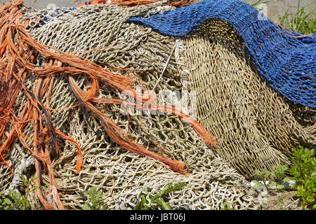 Ein Haufen von alten Fischernetzen hergestellt aus Naturfaser und blau Kunstfaser legen im Hafen. Stockfoto