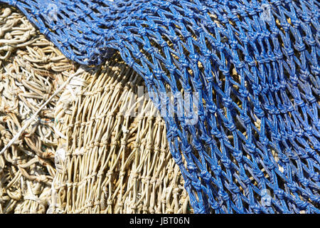 Ein Haufen von alten Fischernetzen hergestellt aus Naturfaser und blau Kunstfaser legen im Hafen. Stockfoto