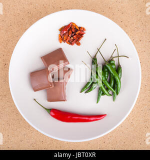 Chilischoten mit Schokolade auf Teller, in hellem Holz Hintergrund. Stockfoto