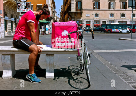 Austräger rufen Sie trägt ein rosa t-Shirt, ruht auf einer Bank und studieren während des Wartens auf eine Lieferung verlangen. Rosa Lieferbox Kurier. Rom, Italien Stockfoto