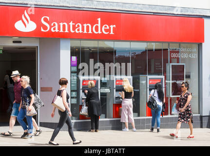 Santander Bank in eine UK-Hauptstraße mit Menschen mit Geldautomaten. Stockfoto