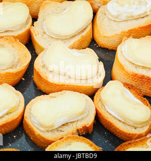 viele gebratene Stücke von Brot mit geschmolzenem Ziegenkäse auf heiße Tablett Stockfoto