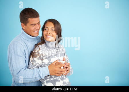 Porträt des glücklichen Paares in modischen Pullover posiert vor blauem Hintergrund Stockfoto