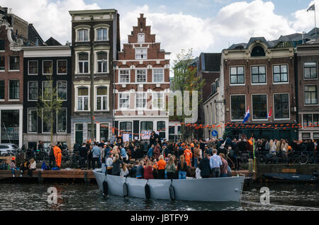 Amsterdam, Niederlande - 25. April 2017: Einheimische und Touristen in orange Kleidung gekleidet fahren auf Booten und an des Königs Tag feiern ein Stockfoto
