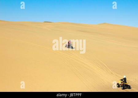 Zwei glückliche Quad Biker fahren in Sanddünen. Junge aktive paar im Freientätigkeit fahren Quad ATV auf Küsten-Wüste Strand, Afrika. Stockfoto