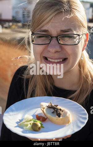 Angewidert Frau mit Eidechse auf dem Teller. Stockfoto