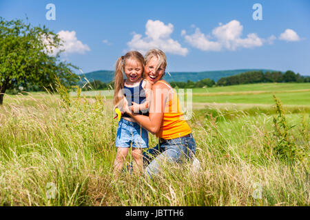 Mutter und Tochter im sonnigen Wiese umarmt einander Stockfoto