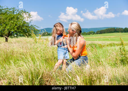 Mutter und Tochter im sonnigen Wiese umarmt einander Stockfoto