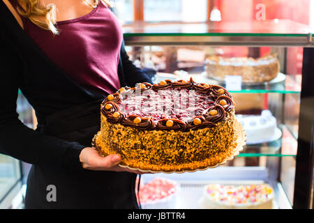 Weibliche Konditor präsentiert Tablett mit Kuchen in der Bäckerei oder Konditorei Stockfoto