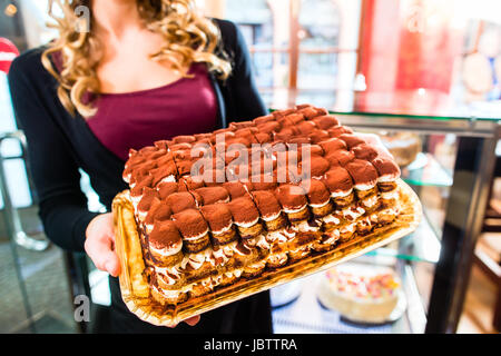 Weibliche Konditor präsentiert Tablett mit Kuchen in der Bäckerei oder Konditorei Stockfoto