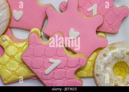 Der erste Geburtstag des Royal icing Cookies - Rosa und Golden Crown geformte Cookies mit der Nummer 1. Stockfoto