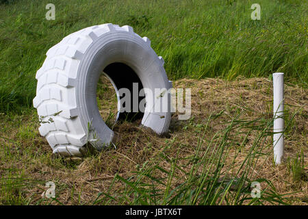 Eine große gebleicht Hinterachse Traktor-Reifen und einen hölzernen Pfahl verwendet als Marker in einem Bauernhof-Feld in Hampshire, England Stockfoto