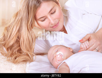 Glückliche junge Mutter liegend mit niedlichen Neugeborenen Baby zu Hause, genießen die ersten Tage der Elternschaft, Ausschreibung, liebevolle Familie, neues Lebenskonzept Stockfoto