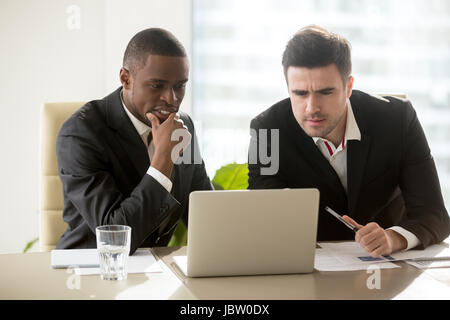 Zwei Geschäftsleute treffen im Blick auf Laptop-Bildschirm, konzentrierte sich auf Präsentation, nachdenklich konzentrierte sich auf die Aufgabe, Abendgarderobe, Problem zu lösen, Stockfoto