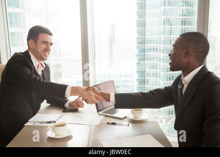 Zwei zufriedene multirassische Geschäftsleute Händeschütteln über Schreibtisch, geteilt Handshake nach effektiven Verhandlungen starten Projekt, afrikanische Ameri Stockfoto