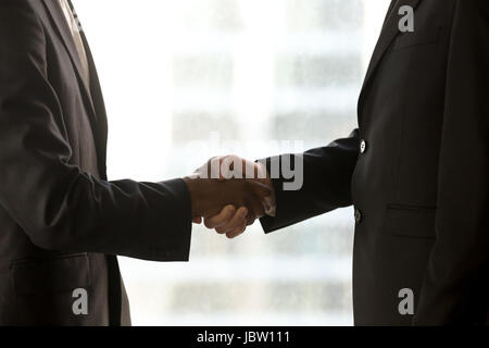 Seitenansicht des schwarzen und weißen Hände schütteln, Geschäftsleute in festlich gekleidet Handshaking, kaukasische und Afro amerikanischen Partner ein Geschäft abgeschlossen, bilden hautnah Stockfoto