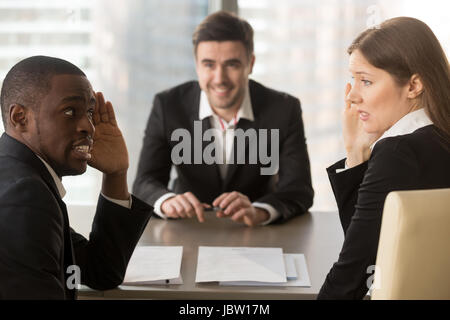 Gemischtrassig verwirrt Arbeitgeber heimlich diskutieren Stellenbewerber, verdeckt Gesicht mit Händen, verwirrten Blick verwirrt, heimlich Flüstern während der gescheiterten interview Stockfoto