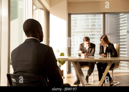 Rückansicht bei afroamerikanischen Bewerber warten auf Ergebnis nach Vorstellungsgespräch während Arbeitgeber oder Personalverantwortliche Kandidatur oder Lebenslauf, schwarz bu betrachten Stockfoto