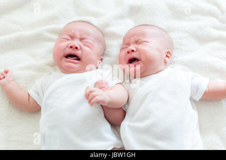 Baby Zwillinge Weinen und auf Bett liegend Stockfoto