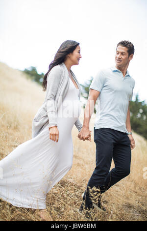 Schwangere Frau und reifer Mann, Hand in Hand, ein Spaziergang durch Feld, Lächeln Stockfoto