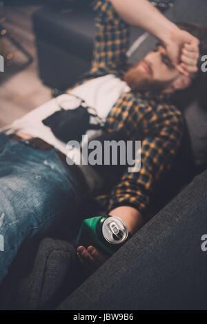 Betrunken bärtiger junger Mann schlafend auf der Couch mit BH und Bier kann nach party Stockfoto