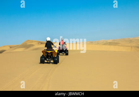 Zwei glückliche Quad Biker fahren in Sanddünen. Junge aktive paar im Freientätigkeit fahren Quad ATV auf Küsten-Wüste Strand, Afrika. Stockfoto