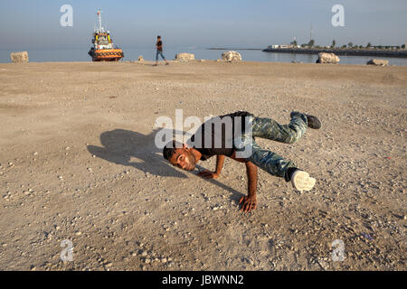 Bandar Abbas, Provinz Hormozgan, Iran - 16. April 2017: der iranische junge Mann zeigt eine Figur, ein Breakdance am Strand des Persischen Golfs. Stockfoto