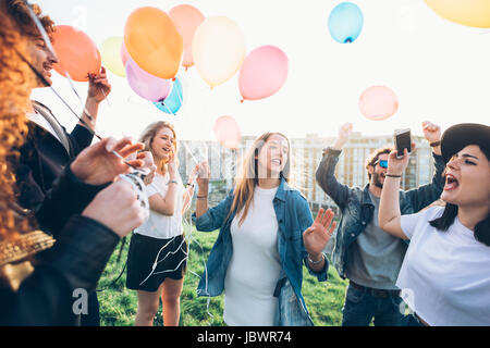 Gruppe von Freunden genießen Dach Partei, Helium-Ballons halten Stockfoto