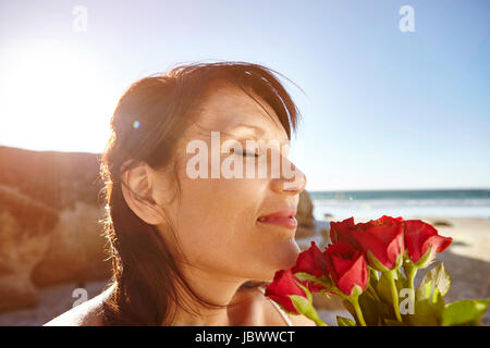 Reife Frau am Strand, duftenden Strauß roter Rosen Stockfoto