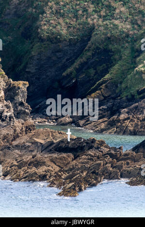 Ein alleines Holzkreuz (1525) namens Schläge Kreuz auf den Felsen an der Ostseite des Eingangs zum Fowey Hafen in Polruan, Cornwall, Großbritannien. Stockfoto