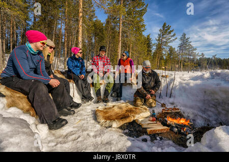 Touristen genießen einen Snack am Lagerfeuer, Lappland Guesthouse, Kangos, Schwedisch Lappland Stockfoto